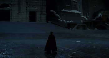 Movie still from “Fellini's Casanova” (1976), directed by Federico Fellini – A man in a black cape standing in front of a building at night; Extreme Wide shot, High angle