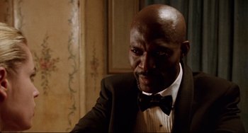 Movie still from “Femme Fatale” (2002), directed by Brian De Palma – A man wearing a suit and bow tie; Close Up shot, Low angle