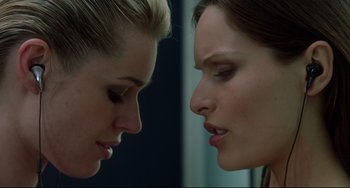 Movie still from “Femme Fatale” (2002), directed by Brian De Palma – Two women looking at each other in the same direction; Close Up shot, Over the shoulder angle