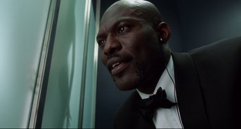 Movie still from “Femme Fatale” (2002), directed by Brian De Palma – A man in a suit and bow tie looking to his left; Close Up shot, Low angle