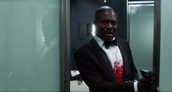 Movie still from “Femme Fatale” (2002), directed by Brian De Palma – A man in a suit and tie with blood on his face; Medium shot, Over the shoulder angle