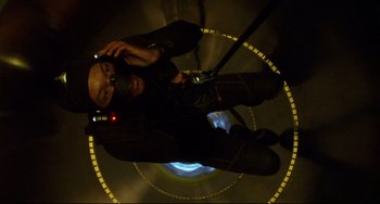 Movie still from “Femme Fatale” (2002), directed by Brian De Palma – A man is standing in the middle of a room; Close Up shot, Overhead angle