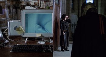 Movie still from “Femme Fatale” (2002), directed by Brian De Palma – A woman standing in front of a computer monitor; Medium shot, High angle