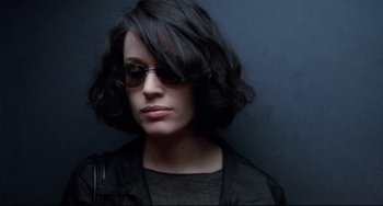 Movie still from “Femme Fatale” (2002), directed by Brian De Palma – A woman wearing glasses and a black leather jacket; Close Up shot, Low angle