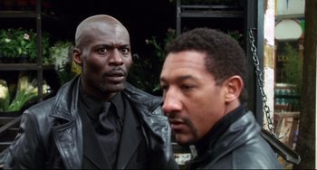 Movie still from “Femme Fatale” (2002), directed by Brian De Palma – Two men in black jackets and ties standing next to each other; Close Up shot, Low angle
