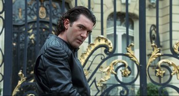 Movie still from “Femme Fatale” (2002), directed by Brian De Palma – A person wearing a jacket near a fence; Medium shot, Low angle