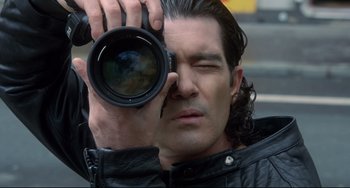 Movie still from “Femme Fatale” (2002), directed by Brian De Palma – A person taking a picture with a camera; Close Up shot, Low angle