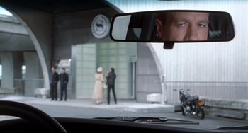 Movie still from “Femme Fatale” (2002), directed by Brian De Palma – A view from a car of a man's reflection in a mirror; Close Up shot, Over the shoulder angle