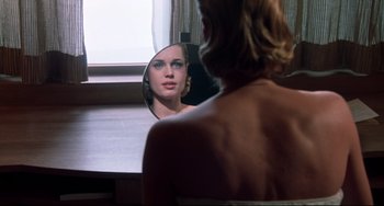 Movie still from “Femme Fatale” (2002), directed by Brian De Palma – A woman looking at her reflection in a mirror; Close Up shot, Over the shoulder angle