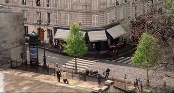 Movie still from “Femme Fatale” (2002), directed by Brian De Palma – People are walking down the sidewalk in front of a building; Extreme Wide shot, High angle