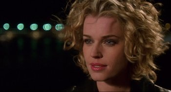 Movie still from “Femme Fatale” (2002), directed by Brian De Palma – A person with curly blonde hair; Close Up shot, Over the shoulder angle