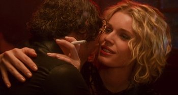 Movie still from “Femme Fatale” (2002), directed by Brian De Palma – A man and a woman kissing while holding a cigarette; Close Up shot, Over the shoulder angle