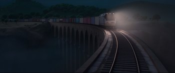 Movie still from “Ferdinand” (2017), directed by Carlos Saldanha – A train traveling down train tracks next to a bridge at night; Extreme Wide shot, High angle