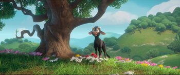 Movie still from “Ferdinand” (2017), directed by Carlos Saldanha – A cow standing next to a tree with flowers around it; Wide shot, High angle