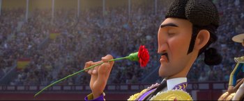 Movie still from “Ferdinand” (2017), directed by Carlos Saldanha – A man holding a flower in his mouth while standing in front of a crowd; Close Up shot, Low angle