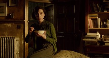 Movie still from “The Shape of Water” (2017), directed by Guillermo del Toro – A woman sitting on a couch holding a bowl of food; Medium shot, Low angle