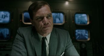 Movie still from “The Shape of Water” (2017), directed by Guillermo del Toro – A man in a suit and tie sitting in front of monitors; Close Up shot, Low angle