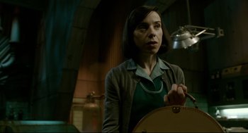 Movie still from “The Shape of Water” (2017), directed by Guillermo del Toro – A woman standing in a room holding a suitcase; Medium shot, Low angle