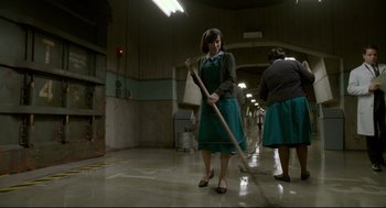Movie still from “The Shape of Water” (2017), directed by Guillermo del Toro – A woman in a green dress is holding a broom; Wide shot, High angle