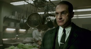 Movie still from “The Shape of Water” (2017), directed by Guillermo del Toro – A man wearing a suit and tie in a kitchen; Close Up shot, Low angle