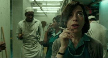 Movie still from “The Shape of Water” (2017), directed by Guillermo del Toro – A woman smoking a cigarette in front of a group of people; Close Up shot, Over the shoulder angle