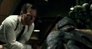 Movie still from “The Shape of Water” (2017), directed by Guillermo del Toro – A man in white shirt and tie next to a blue creature; Medium shot, Over the shoulder angle