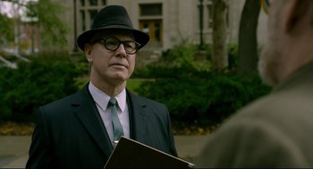 Movie still from “The Shape of Water” (2017), directed by Guillermo del Toro – An older man in a suit and tie holding a book; Close Up shot, Over the shoulder angle