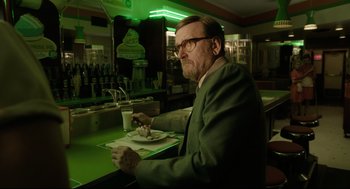 Movie still from “The Shape of Water” (2017), directed by Guillermo del Toro – An older man sitting at a table with a plate of food; Medium shot, Over the shoulder angle