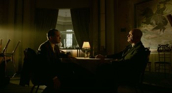 Movie still from “The Shape of Water” (2017), directed by Guillermo del Toro – Two men sitting at a table in front of a lamp; Medium shot, Low angle