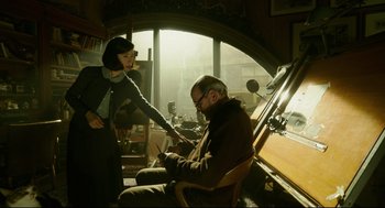 Movie still from “The Shape of Water” (2017), directed by Guillermo del Toro – A man sitting in front of a woman holding a pen; Medium shot, Low angle