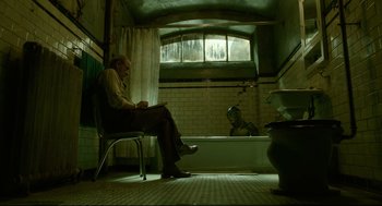 Movie still from “The Shape of Water” (2017), directed by Guillermo del Toro – An old man sitting on a chair in a bathroom; Wide shot, Low angle