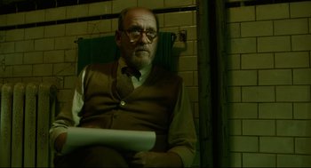 Movie still from “The Shape of Water” (2017), directed by Guillermo del Toro – An older man sitting in a chair in a room; Medium shot, Over the shoulder angle