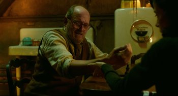 Movie still from “The Shape of Water” (2017), directed by Guillermo del Toro – An older man sitting at a dining table; Medium shot, Over the shoulder angle