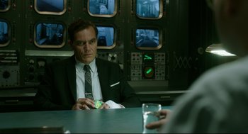 Movie still from “The Shape of Water” (2017), directed by Guillermo del Toro – A man sitting at a table in a room; Medium shot, Over the shoulder angle