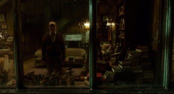 Movie still from “The Shape of Water” (2017), directed by Guillermo del Toro – A man standing in front of a window with a lot of books; Wide shot, Low angle