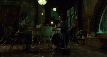 Movie still from “The Shape of Water” (2017), directed by Guillermo del Toro – A woman sitting at a table in a dark room; Wide shot, High angle