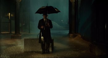 Movie still from “The Shape of Water” (2017), directed by Guillermo del Toro – A man holding an umbrella while standing in the rain; Wide shot, Low angle