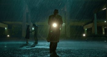 Movie still from “The Shape of Water” (2017), directed by Guillermo del Toro – A man standing in the rain holding a flashlight; Wide shot, Low angle
