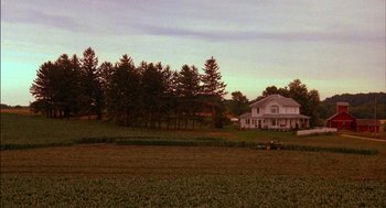 Movie still from “Field of Dreams” (1989), directed by Phil Alden Robinson – A large house sitting on top of a lush green field; Extreme Wide shot, High angle