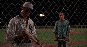 Movie still from “Field of Dreams” (1989), directed by Phil Alden Robinson – Two baseball players standing next to each other on a baseball field at night; Medium shot, Over the shoulder angle