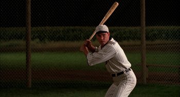 Movie still from “Field of Dreams” (1989), directed by Phil Alden Robinson – A baseball player holding a baseball bat on top of a baseball field; Medium shot, Over the shoulder angle