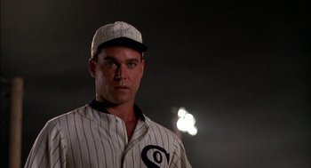 Movie still from “Field of Dreams” (1989), directed by Phil Alden Robinson – A baseball player in a white pinstriped baseball uniform; Close Up shot, Low angle
