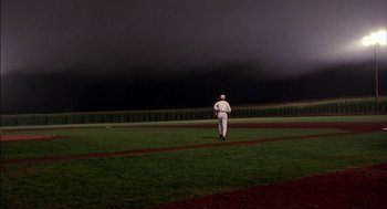 Movie still from “Field of Dreams” (1989), directed by Phil Alden Robinson – A baseball player walking across a field at night; Extreme Wide shot, Over the shoulder angle