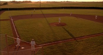 Movie still from “Field of Dreams” (1989), directed by Phil Alden Robinson – A baseball game is being played on a grassy field; Extreme Wide shot, High angle