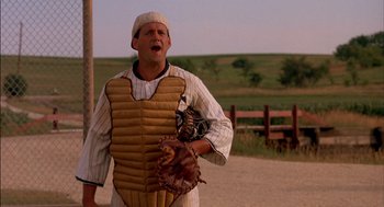 Movie still from “Field of Dreams” (1989), directed by Phil Alden Robinson – A baseball player wearing a catcher's mitt and baseball uniform; Medium shot, Over the shoulder angle
