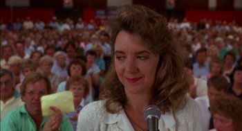 Movie still from “Field of Dreams” (1989), directed by Phil Alden Robinson – A woman is speaking at a public speaking event; Close Up shot, Over the shoulder angle