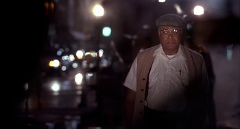 Movie still from “Field of Dreams” (1989), directed by Phil Alden Robinson – An older man wearing glasses and a hat is standing in the street; Medium shot, Low angle