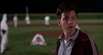 Movie still from “Field of Dreams” (1989), directed by Phil Alden Robinson – A young man standing on top of a baseball field; Close Up shot, Over the shoulder angle