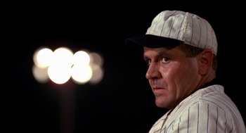 Movie still from “Field of Dreams” (1989), directed by Phil Alden Robinson – A baseball player in a white and black uniform; Close Up shot, Low angle
