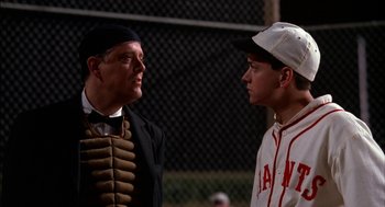 Movie still from “Field of Dreams” (1989), directed by Phil Alden Robinson – Two baseball players talking to each other in front of a chain link fence; Medium shot, Over the shoulder angle